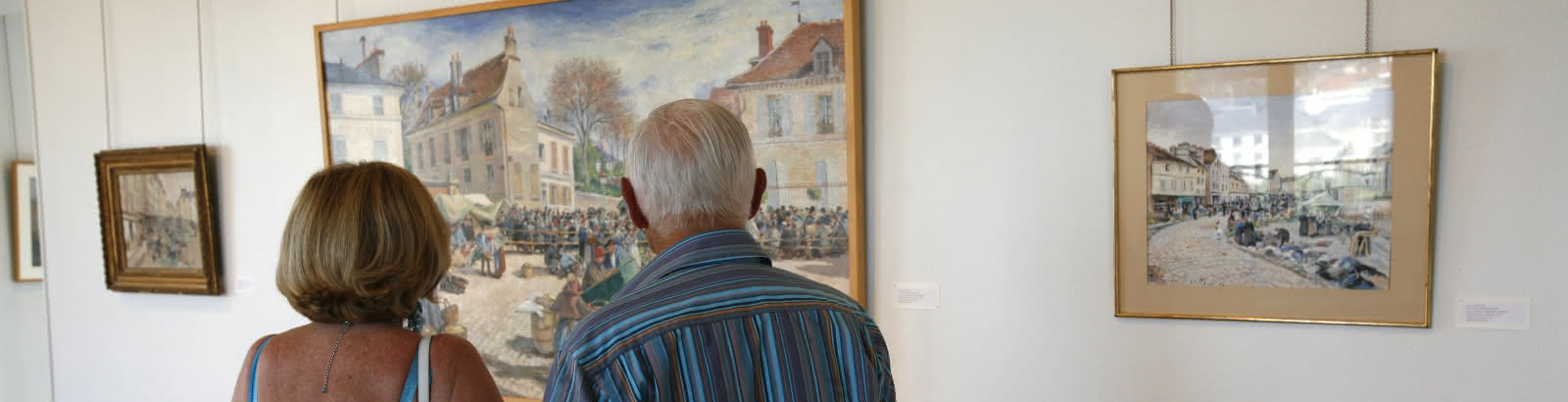 Photo de deux personnes regardant des tableaux pendant leur visite du musée Pissarro à Pontoise