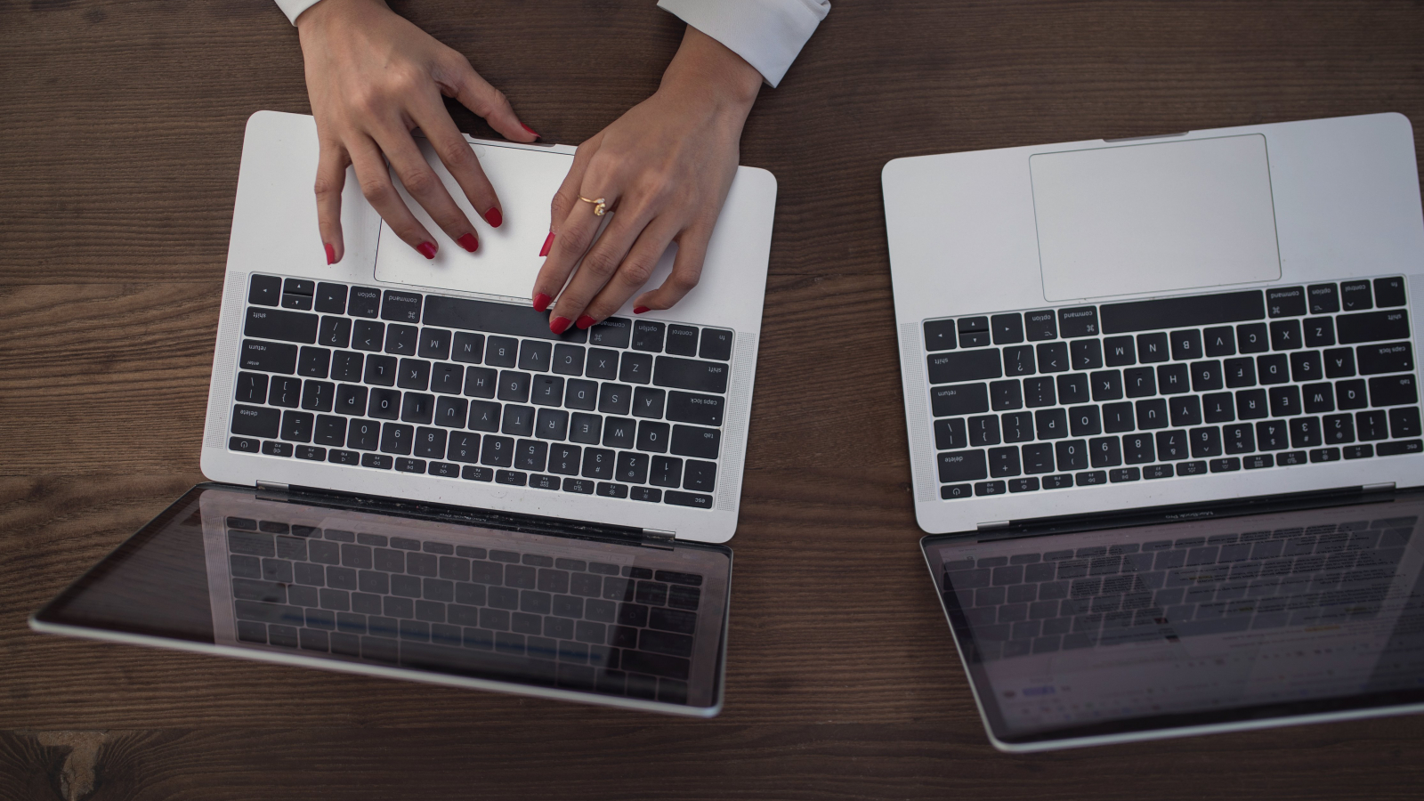 Photo de mains féminines utilisant un ordinateur près d'un autre ordinateur également ouvert