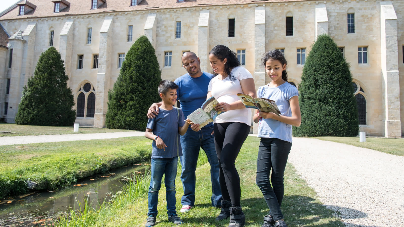 Photo d'une famille de deux parents et deux enfants en train de découvrir le contenu des carnets de visite dans le parc