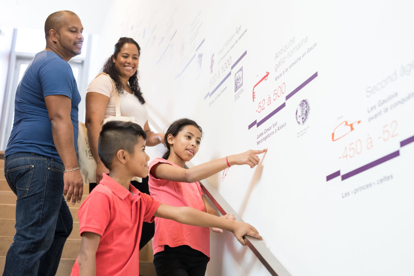 Photo d'une famille au musée Archéa à Louvres avec une guide de musée qui explique ce qu'il y a en vitrine