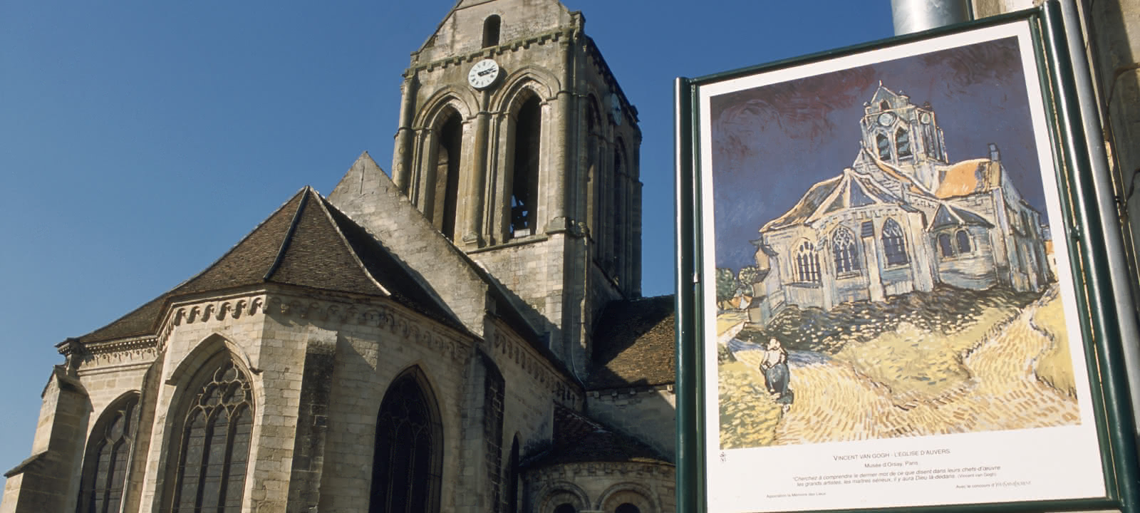 Photo de l'église d'Auvers-sur-Oise avec un panneau représentant un tableau de Vincent Van Gogh