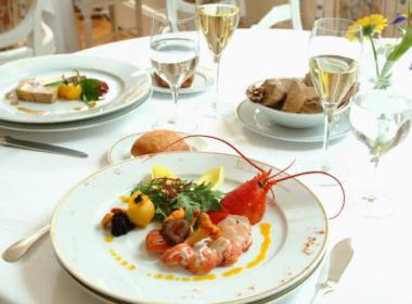 Photo de deux assiettes gastronomiques et verres de vin sur une table bien dressée au restaurant les Jardins d'Epicure